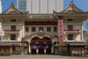 “Front view of the Kabuki-za Theatre in Ginza, Tokyo, featuring its traditional white facade, ornate tiled roof, red balcony accents, and purple curtain at the entrance under a clear blue sky.”